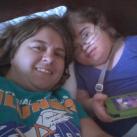 woman laying down next to her daughter playing on an ipad