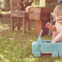 A boy with Down syndrome playing with toy truck outside on grass