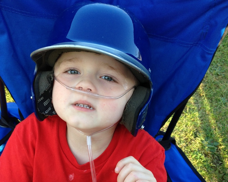 boy with mitochrondrial disease wearing a t-ball helmet