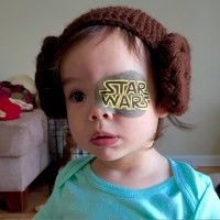 Small female toddler with a 'Star Wars' eye patch and ear muffs on
