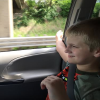 Author's son riding in the passenger seat of a car with window down.