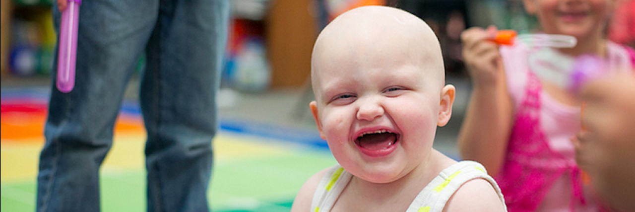Young girl with a big smile and bald head