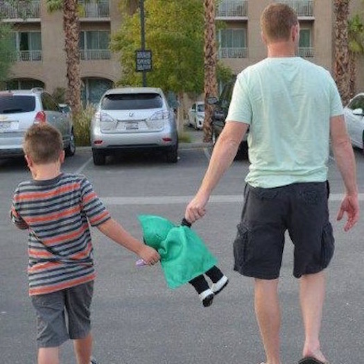 Father and son in a parking lot. Both are holding a toy.