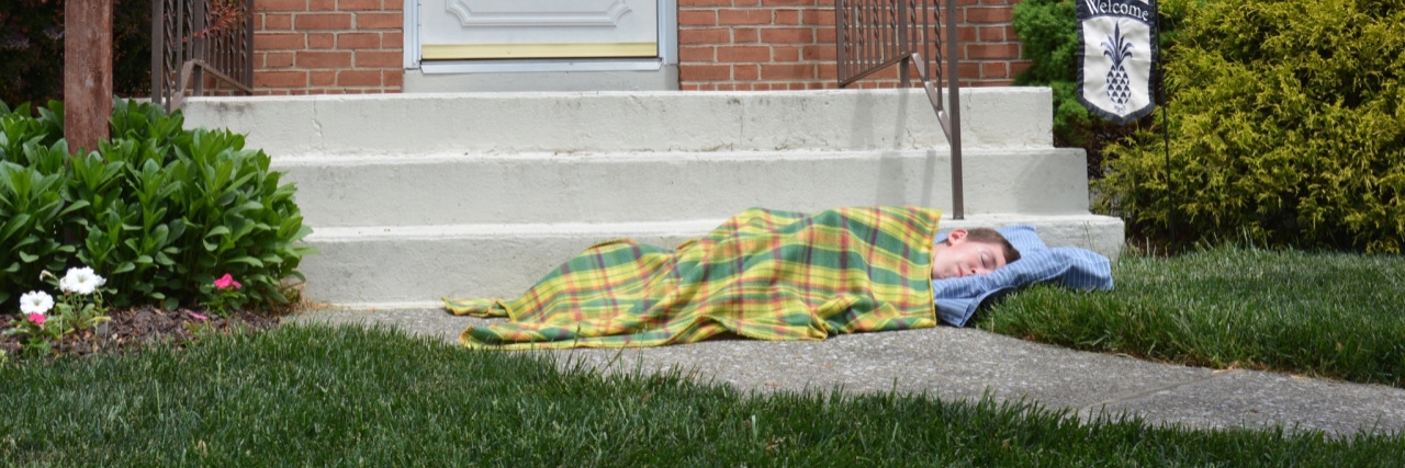 Meme of boy laying in front of porch with blankets that says, "This is where I'd sleep if my house had no wheelchair ramp."