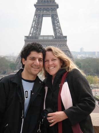 husband and wife standing in front of the eiffel tower