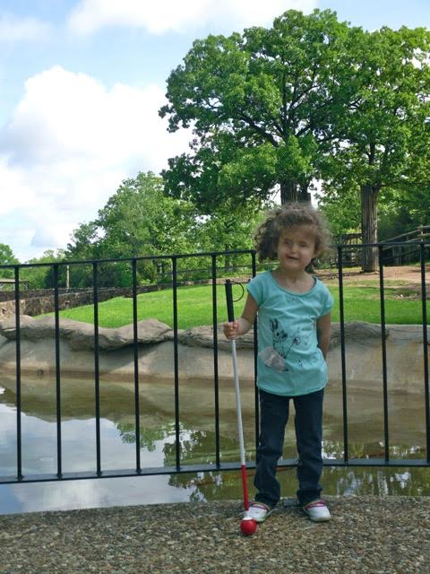 young girl standing in front of a pond