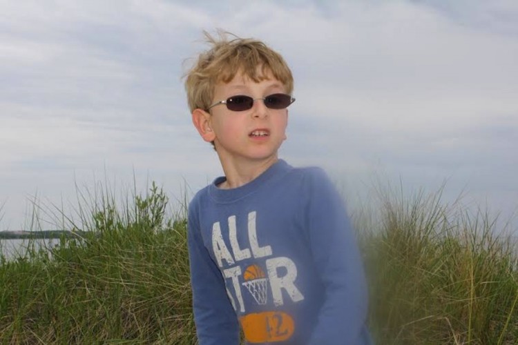 young boy with glasses on the beach