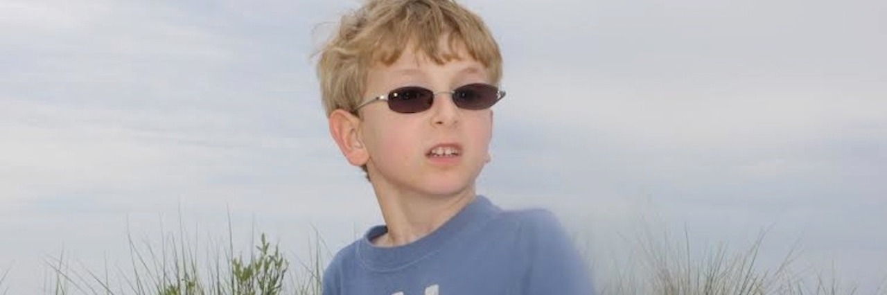 young boy with glasses on the beach