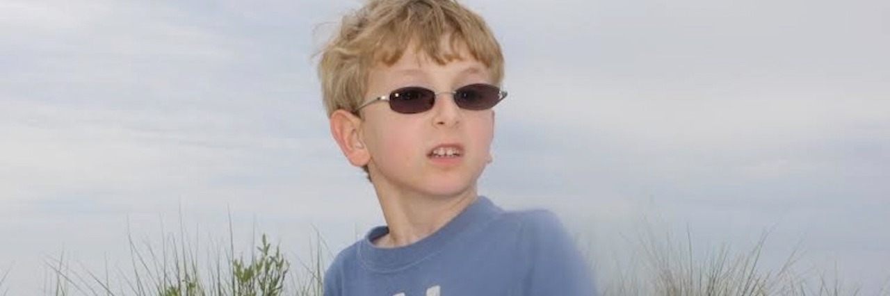How My Son With Autism Can Help Educate Other Children young boy with glasses on the beach