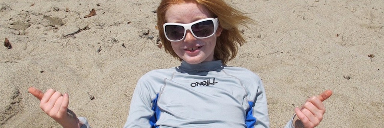 Going to the Beach With a Child With Sensory Processing Disorder young girl at the beach buried in the sand