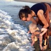 The author with her son at the beach. He's dipping his toes in water while she holds him.
