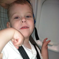 A small seated on a plane next to the window