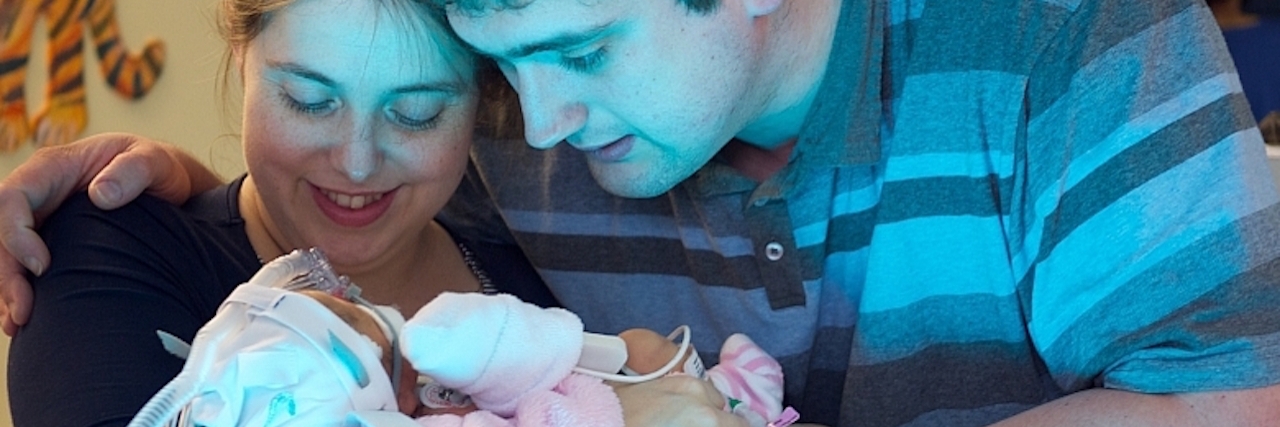 A couple looking down at their newborn baby