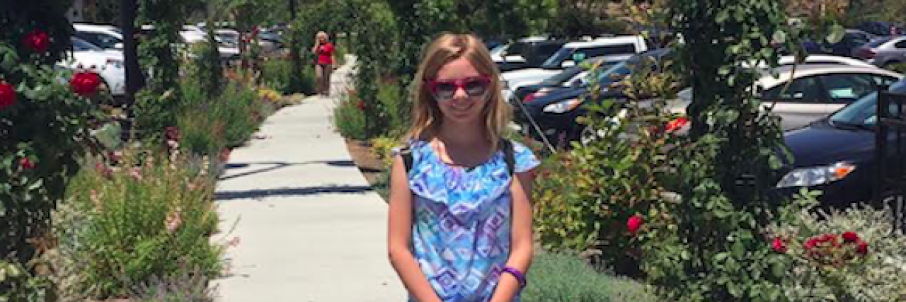 What 'Treat and Street' Means for My Daughter Who Has Bipolar Young girl standing on sidewalk surrounded by plants and archways behind her