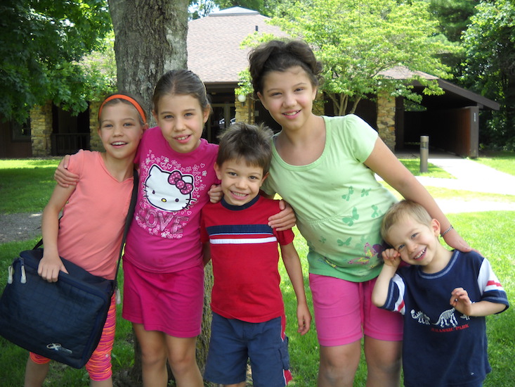 five children smiling and hugging outside