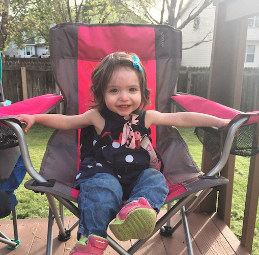 young girl sitting in a chair outside