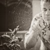 An older man looking at a spider web and reaching out to touch it