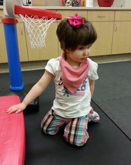 author's daughter sitting next to play basketball hoop