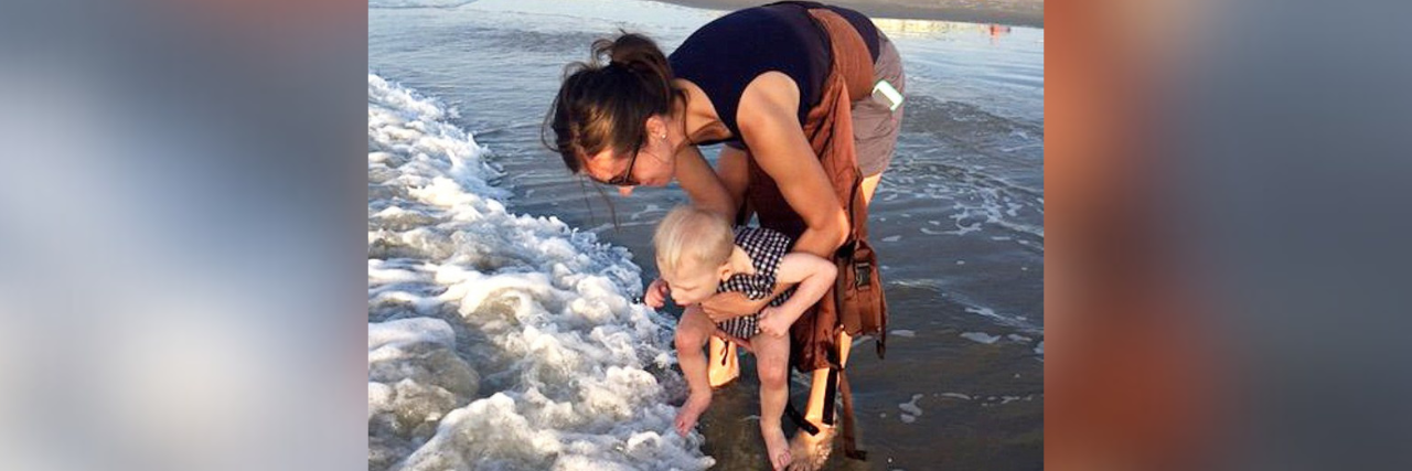 Mom Questioned for Handicapped Parking Spot Use Responds Mother holding child to dip their toes in the water at the beach