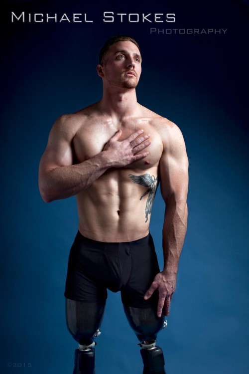 shirtless man with prosthetic legs, posing with hand over his heart