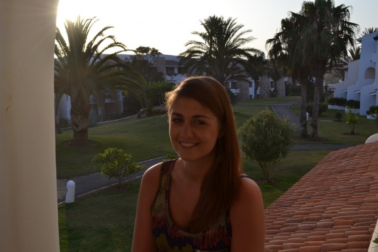 young woman poses for photo on balcony