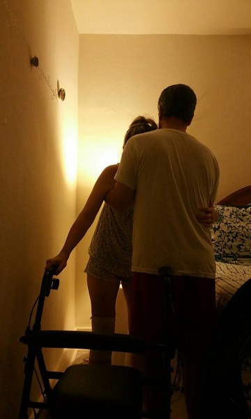 Husband helps his wife to her walker. 