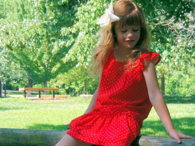 little girl in red dress sitting outside