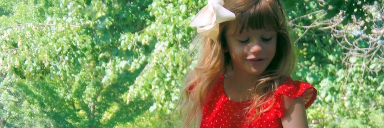 Learning From the Reminders of My Child’s Chronic Illness little girl sitting outside in red dress