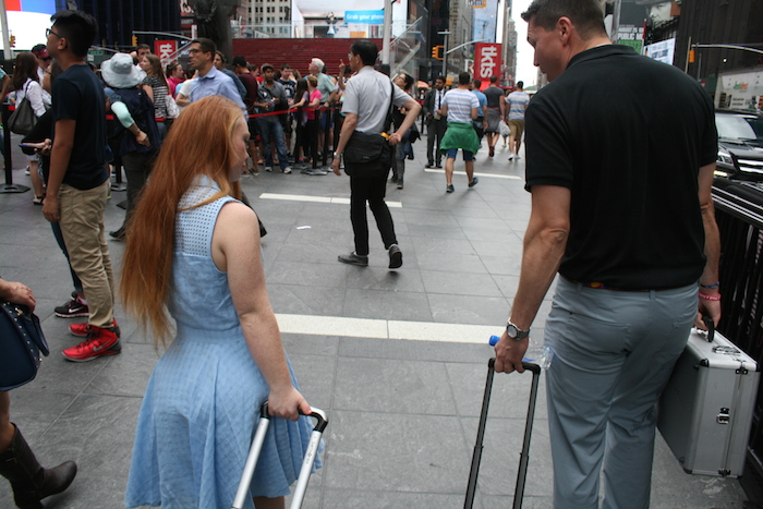 Madeline Stuart and Damian Graybelle pulling rolling suitcases on a New York street