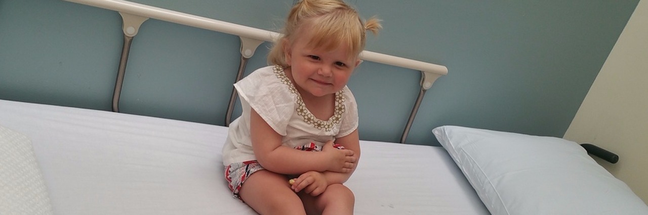 Advice for Parents Who Found Out Their Child Has Cancer author's daughter sitting on a hospital bed