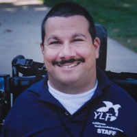 A man smiling as he is seated in his wheelchair