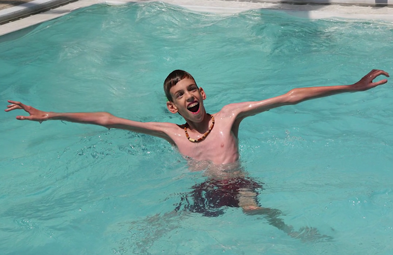 photograph of young boy swimming in a pool