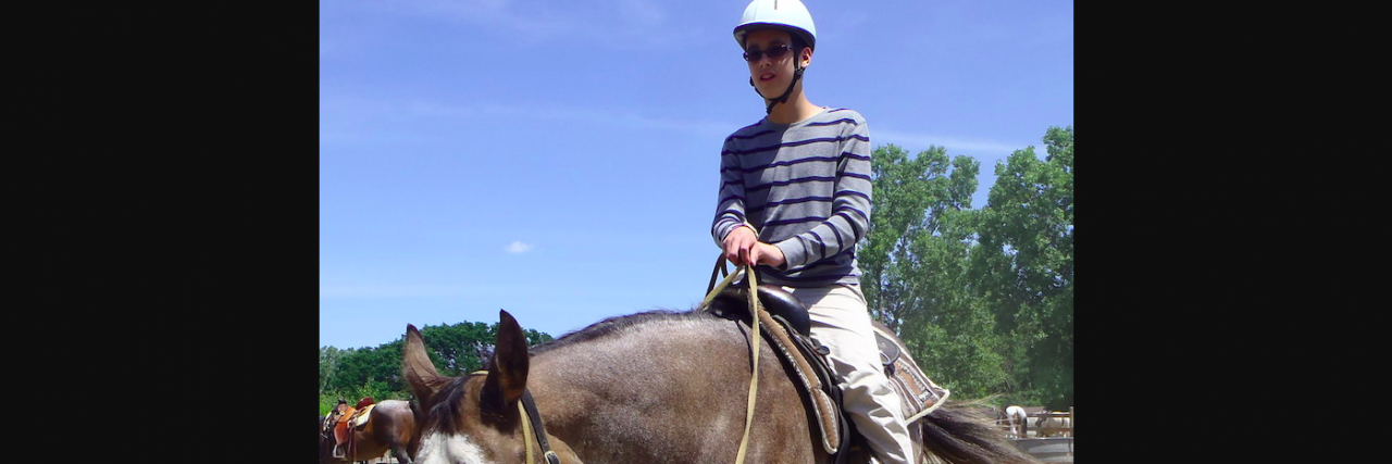 Boy riding a horse and wearing a helmet