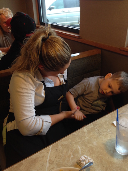 A waitress holding hands with a boy who has cerebral palsy.