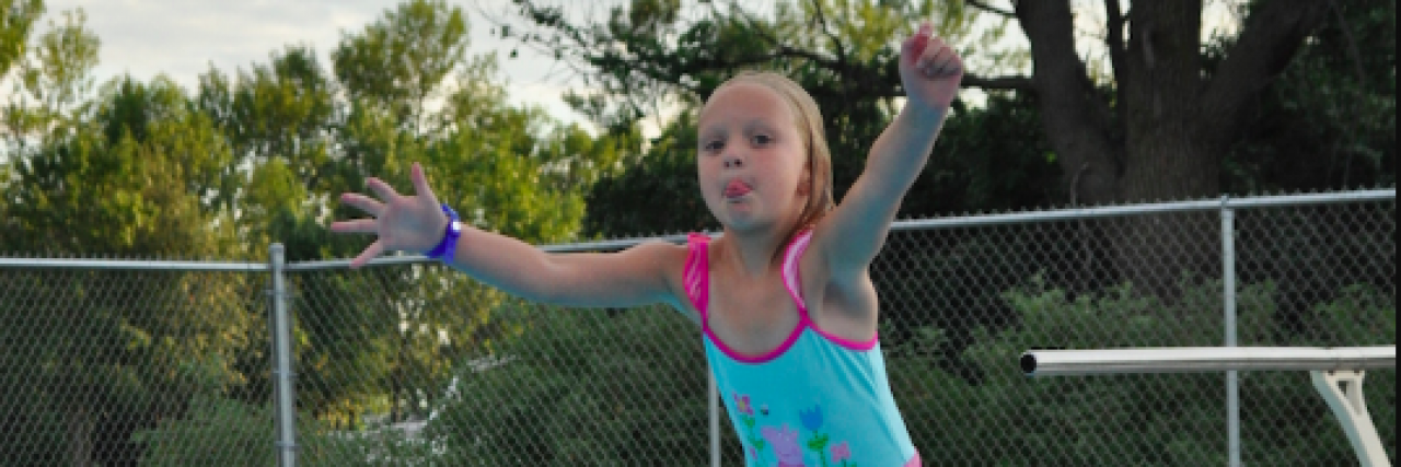 Swim Instructor Helps Girl With Epilepsy and Seizures Love the Water Young girl jumps off of diving board into a pool