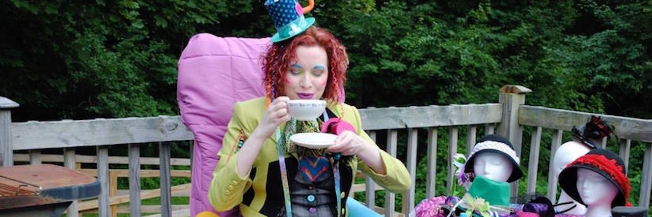 How Cosplay Changed My Life With Chronic Illness A young woman in a costume sipping on tea in her wheelchair next to a table covered with more costume iterms