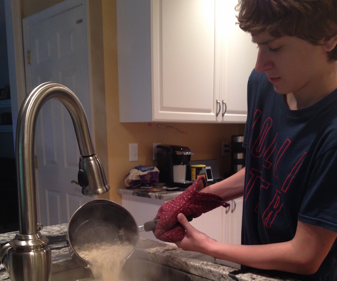 Kathy's son draining cooked pasta in the sink