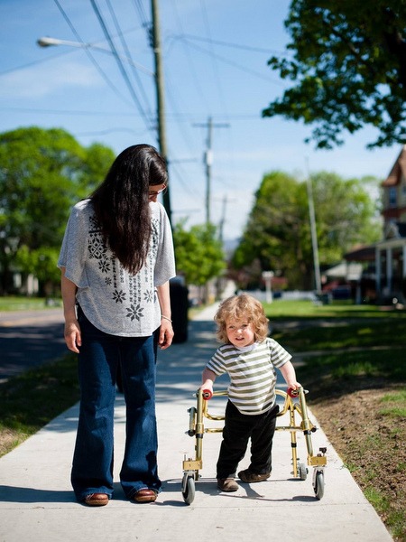 Mom walking with her son in a neighborhood. Her son uses a wheelchair. 