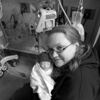 A mom holding her newborn in blankets and a hat at the hospital