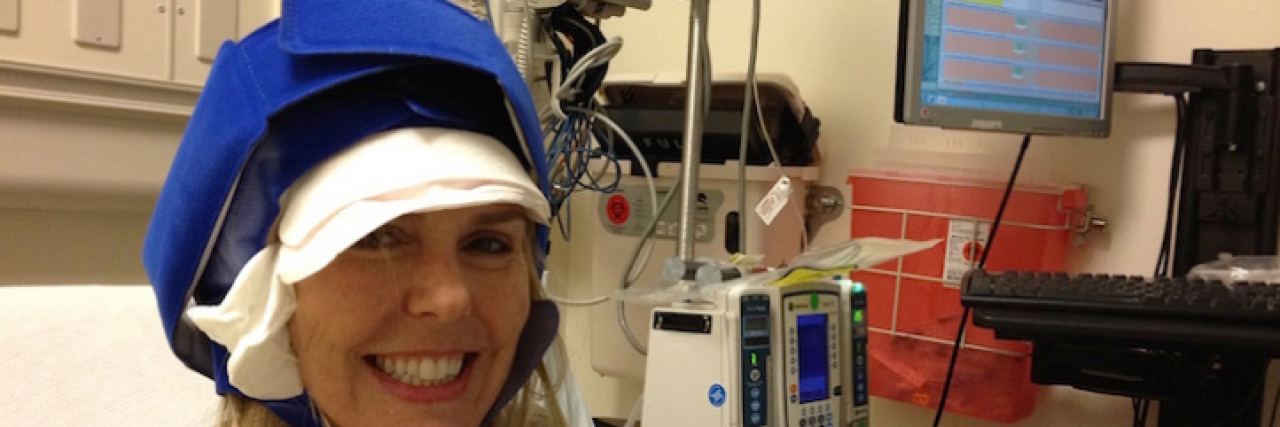 Contributor wearing a chemo cap and blanket in hospital room, while smiling