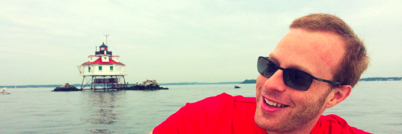 What It’s Like to Walk in My Shoes as a Person With Meniere’s Disease Man sitting on boat near lighthouse