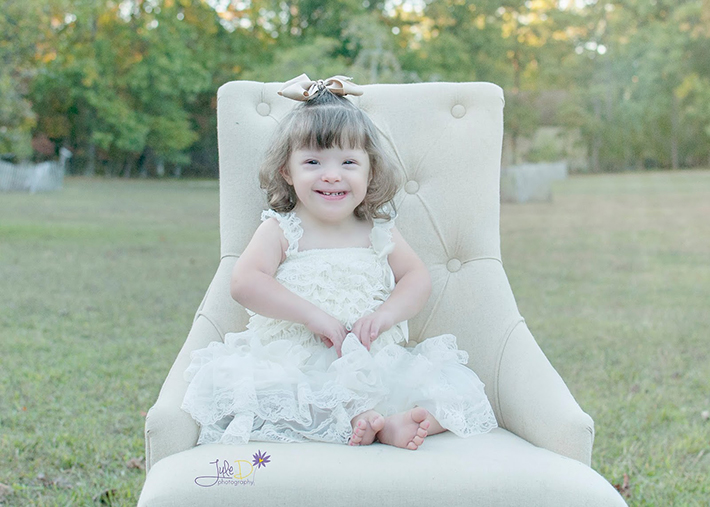 Girl wearing white dress sitting in a chair in a park