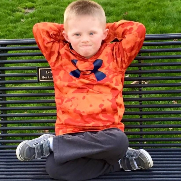 young boy on park bench with arms behind head