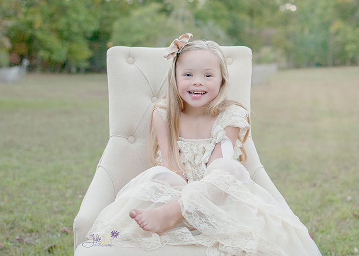 Girl wearing white dress sitting on chair outside