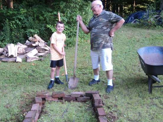 A young boy and his grandfather, they're both holding shovels.