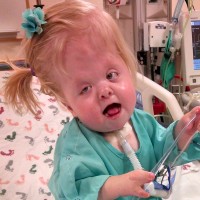 a young girl sitting on a bed in a hospital room