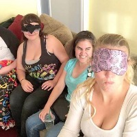 Caitlin's description of the image: "A selfie a sighted friend took when she and three other sighted friends put on blindfolds and watched a movie with me using video description."