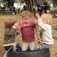Three girls playing on a tire swing