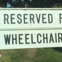 A sign that says, :Reserved for wheelchair users," with the word fat graffited on it