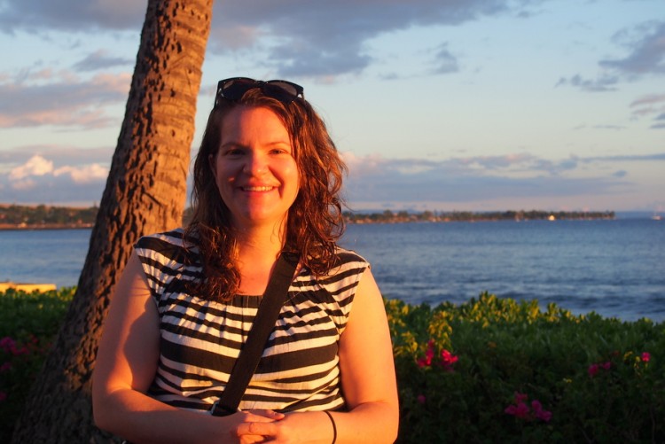 Woman smiles in front of a body of water. 